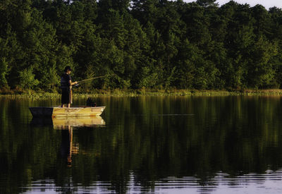 Man fishing while standing on boat in lake