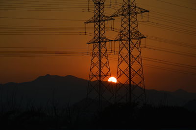 Silhouette electricity pylon against sky during sunset