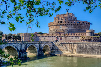 Arch bridge over river against blue sky