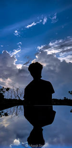 Silhouette man standing by lake against sky