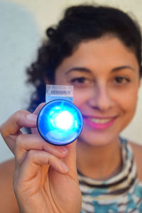 Close-up portrait of a smiling young woman holding camera