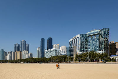 People on modern buildings against clear blue sky