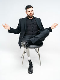 Young man sitting on chair against white background