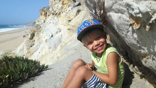 Portrait of happy girl sitting on rock at beach