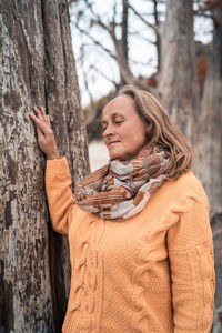 Midsection of woman standing by tree trunk