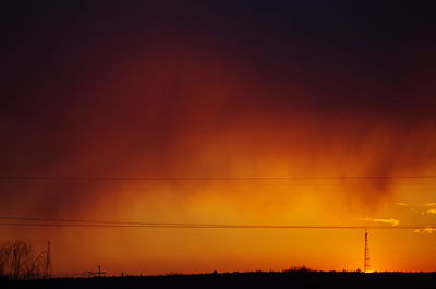 Silhouette of electricity pylon against romantic sky at sunset