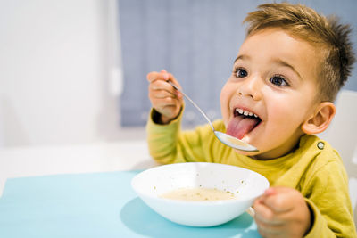 Close-up of smiling boy sticking out tongue while eating soup