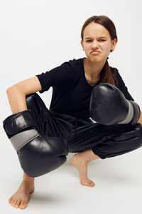 Portrait of young woman exercising against white background