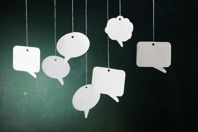 Close-up of speech bubbles hanging against wall