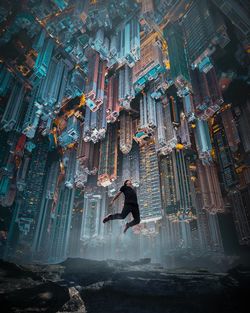 Digital composite image of man jumping on mountain against cityscape at night