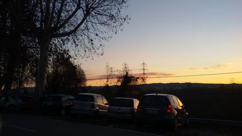 Cars on street against sky during sunset