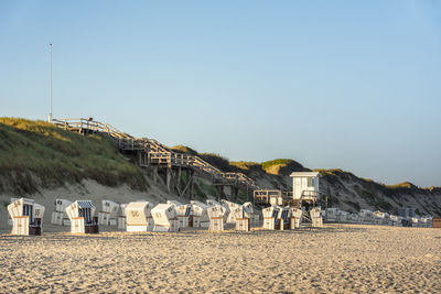 Hooded chair on beach against sky