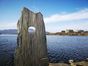 Wooden posts in sea against sky