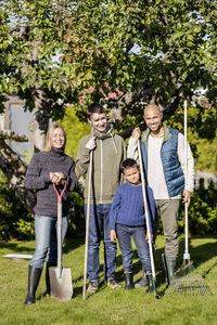 Full length portrait of a smiling girl standing against plants