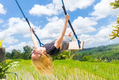 Woman with arms raised on field against sky