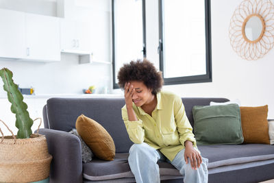 Young woman sitting on sofa at home