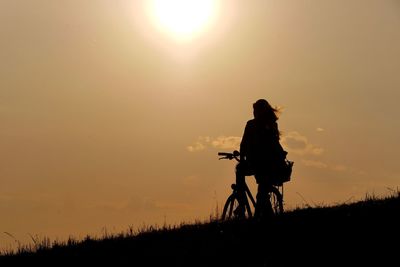 Silhouette woman bicycling against the sky