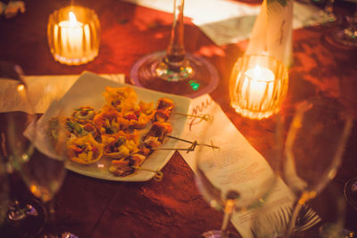 Lit candles by food in tray on table at restaurant