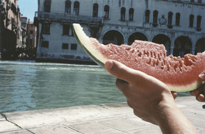 Cropped image of hand against buildings in city