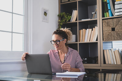 Young woman using laptop while sitting in library