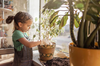 Girl looking away while standing on potted plant