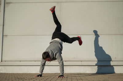 Full length of young woman jumping against wall