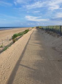 Road leading towards beach against sky