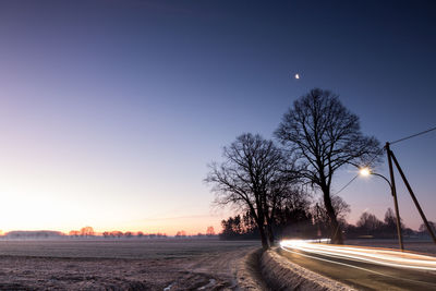 Road by trees against sky at night