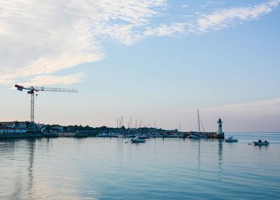 Sailboats moored in harbor against sky