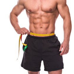 Midsection of shirtless man standing against white background