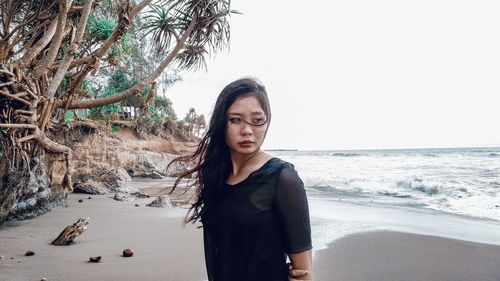 Portrait of young woman by sea against sky