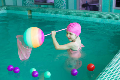 Girl playing with plastic balls in swimming pool