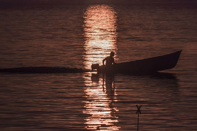 Silhouette of people in water at sunset