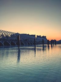 Bridge over river against clear sky during sunset