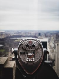 Close-up of coin-operated binoculars against cityscape