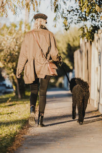 Rear view of woman with dog walking outdoors