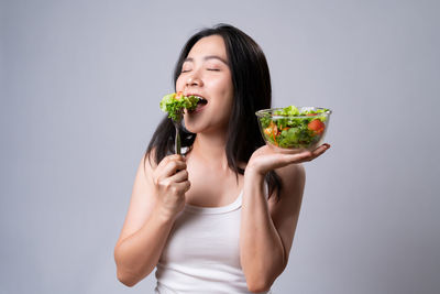 Young woman holding fruit against white background