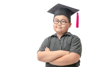 Portrait of boy wearing mortarboard against white background