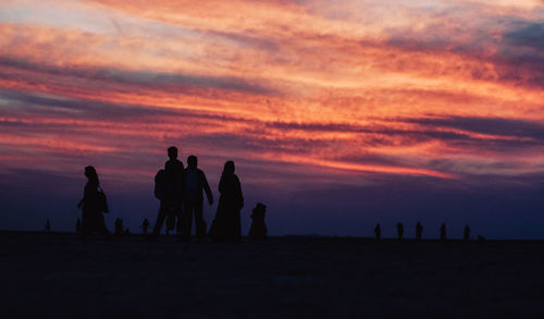 Silhouette people on beach against sky during sunset