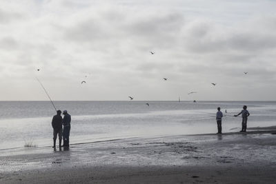 Silhouette people on beach against sky