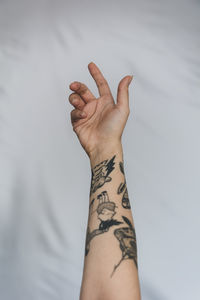 Close-up of woman's hand with tattoo against white background