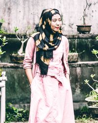 Portrait of smiling young woman standing against plants