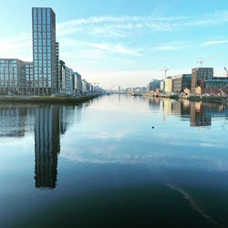 Buildings by river against sky in city