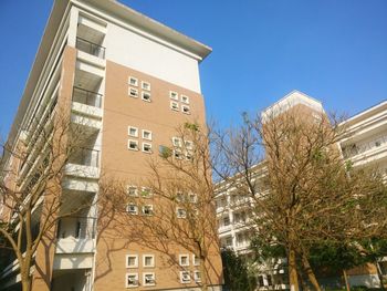 Low angle view of apartment building against clear blue sky