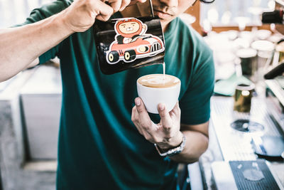 Midsection of young man pouring coffee in cup