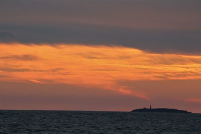 Scenic view of sea against cloudy sky during sunset