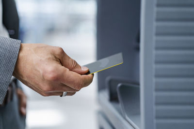 Hand of businessman holding credit card near atm machine