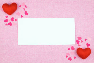 Close-up of heart shapes and paper on pink background