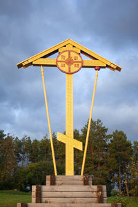 Low angle view of cross in park against sky