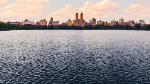 Jacqueline kennedy onassis reservoir lake in central park at sunset. nyc skyline at background. nyc